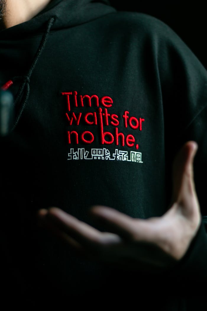 Close-up of a black hoodie with 'Time waits for no one' slogan